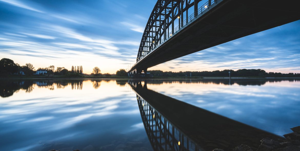 A beautiful shot of a bridge over a reflective lake during the sunset